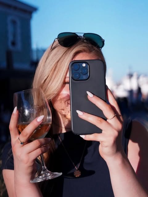 Morgan holding up a phone and a glass of wine in Cape Town